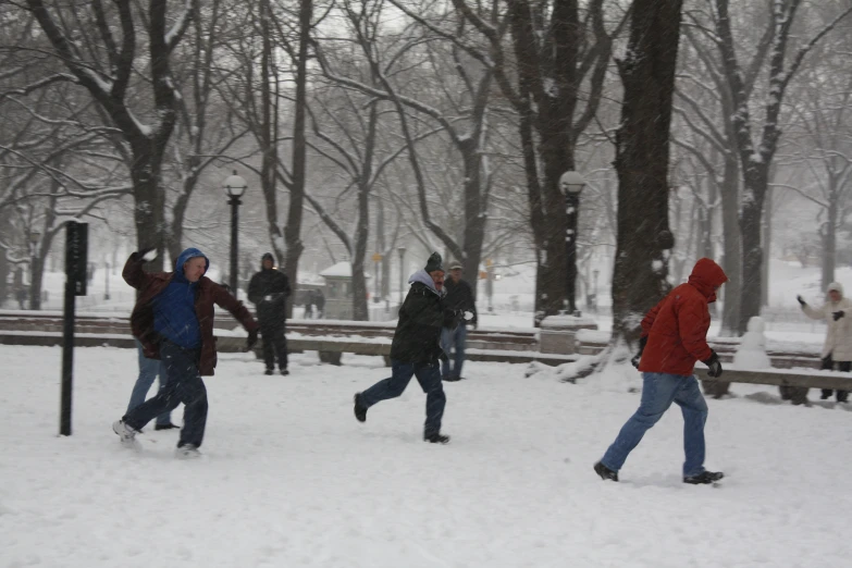 group of people walking through the snow in a park