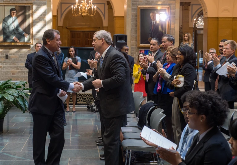 two men shake hands in front of a crowd