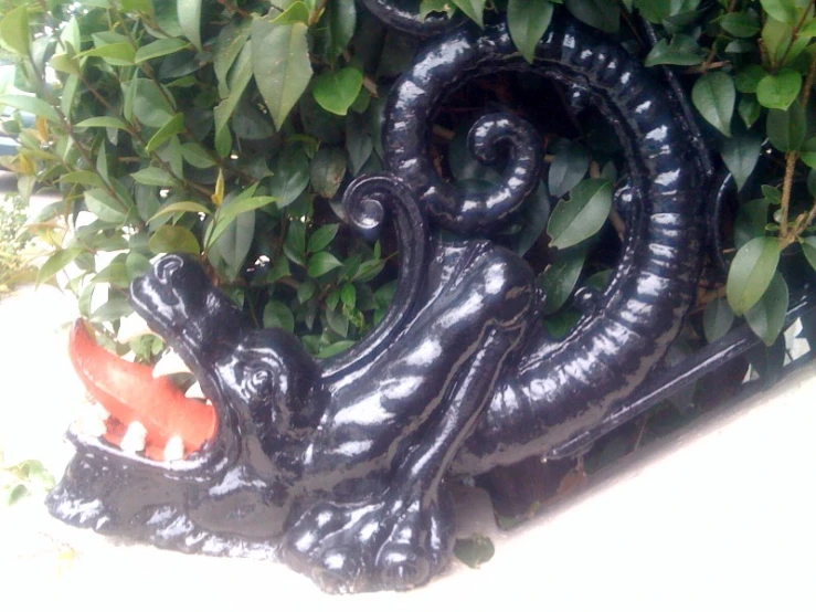 this black decorative piece has a lizard shaped tail on it's head