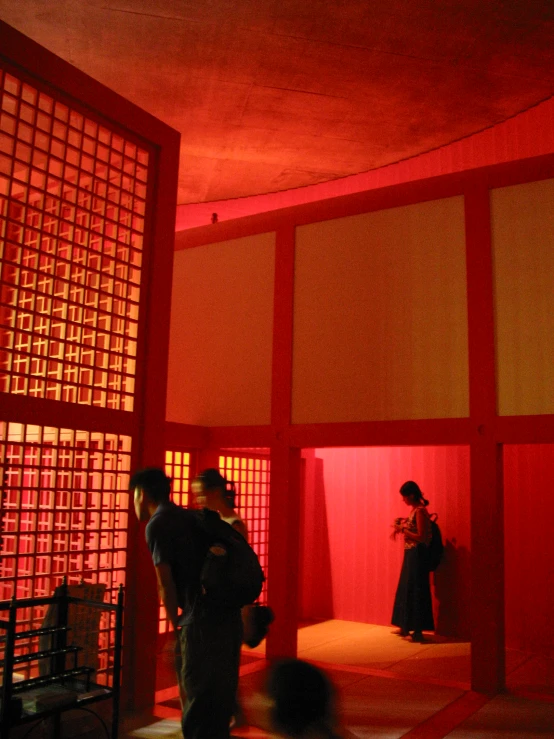 two people standing in a room with red lights and screen behind them