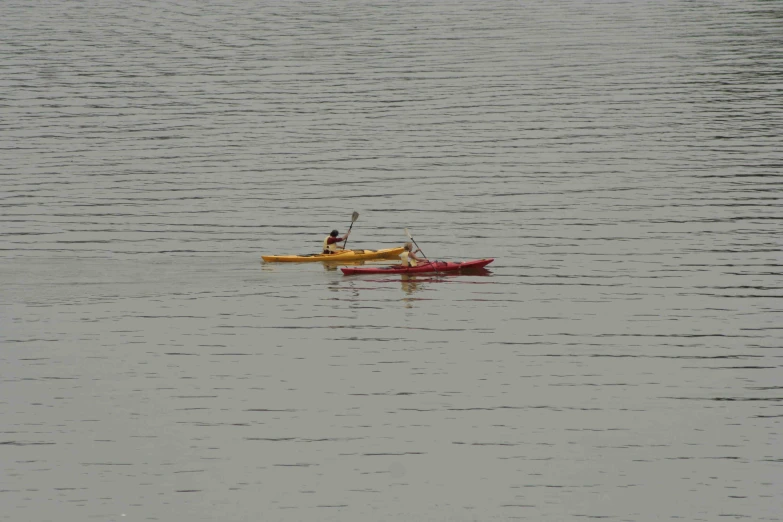 two men in red canoes paddling across the water