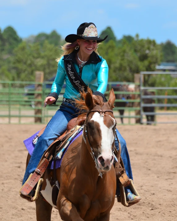 a girl riding a brown and white horse on dirt ground