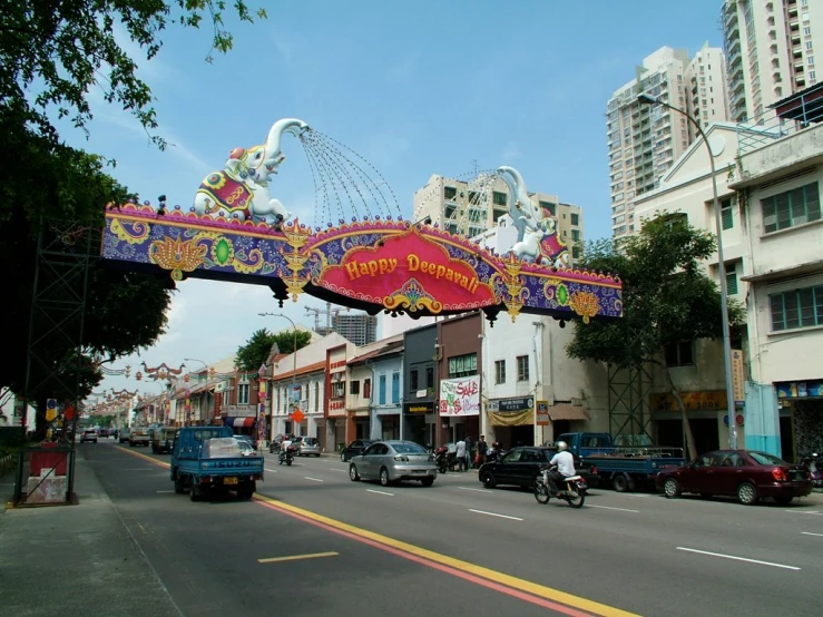 a colorfully decorated sign above cars driving down a road