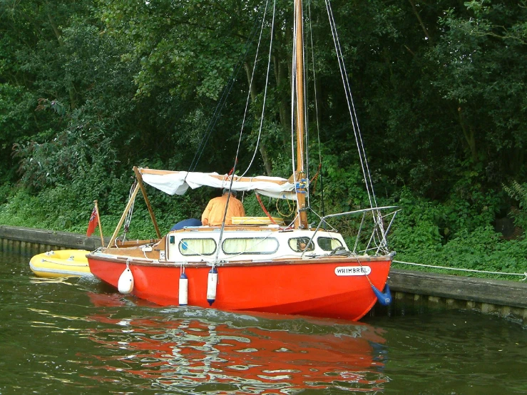 red boat sits on water next to a dock