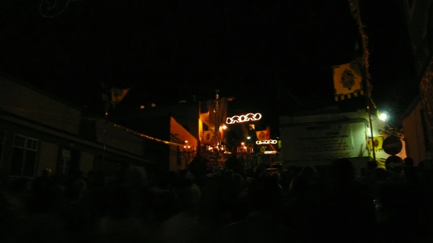 a crowd of people standing on a street at night