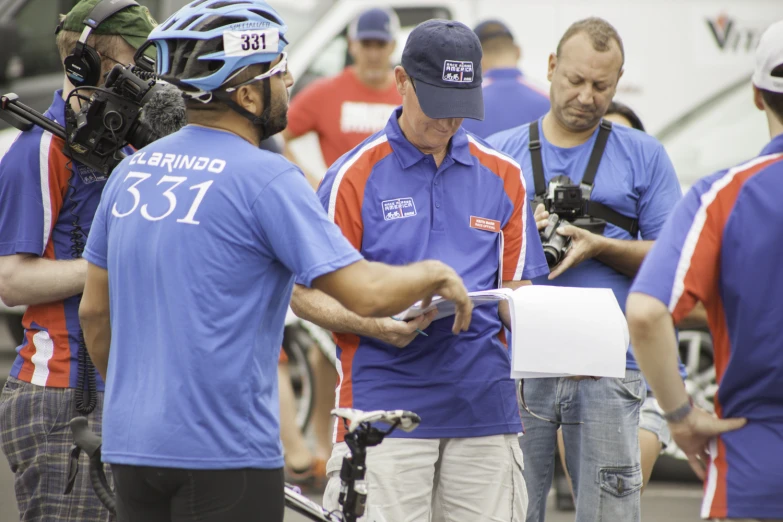 two men in blue shirts are recording other men