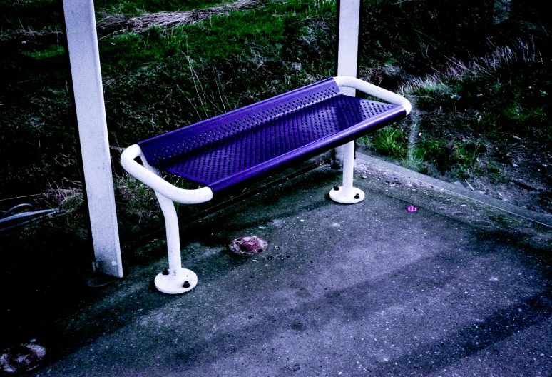 a purple bench with white piping sitting in a parking lot