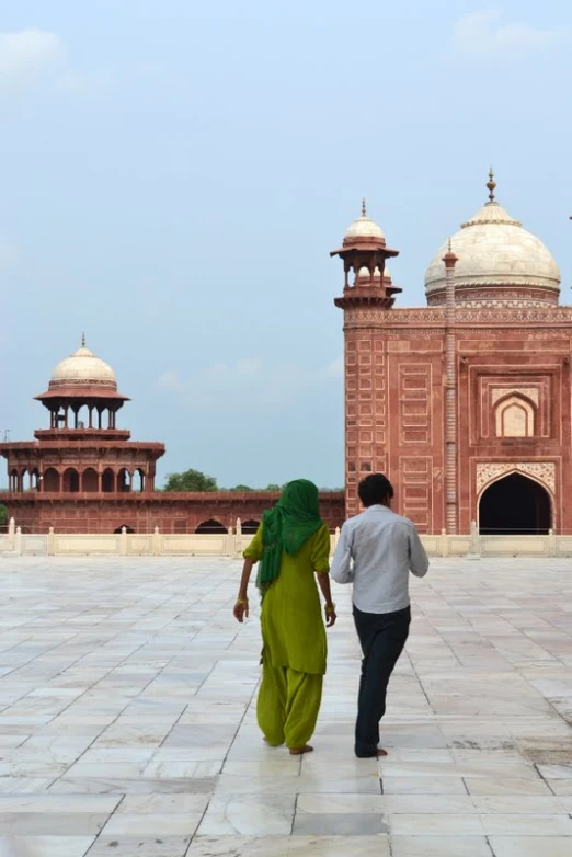 a couple walking across a cement platform towards the minalis of a large building