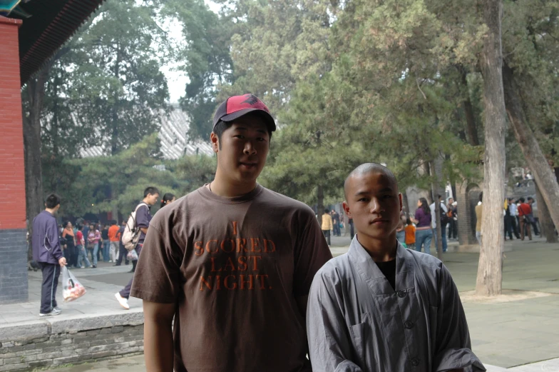 two young men are standing in front of the trees