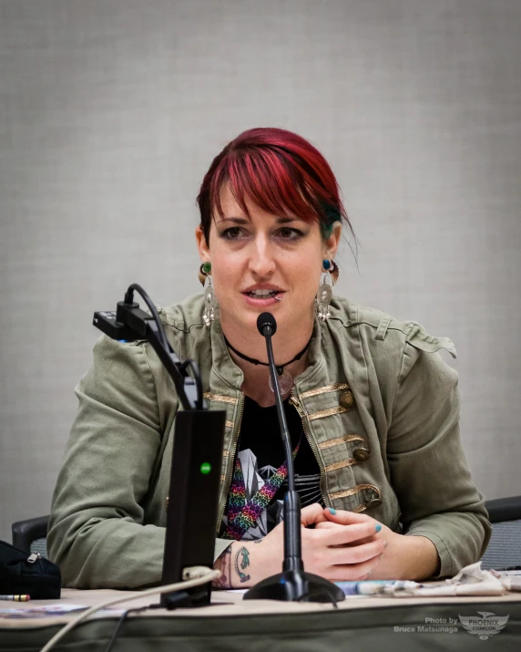 a woman in a green jacket at a microphone