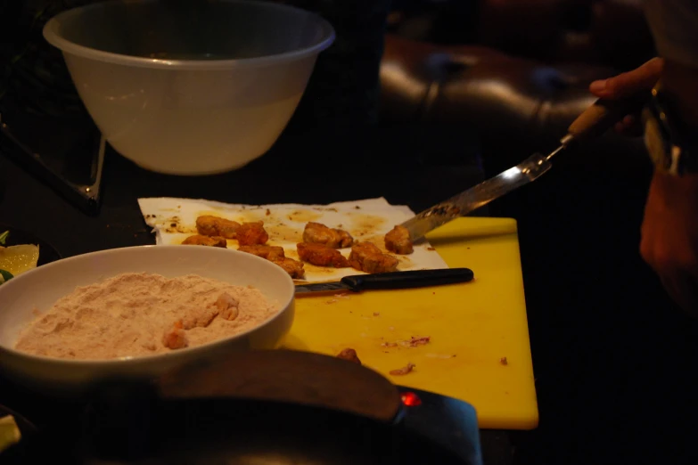 person slicing meat and other items on a  board