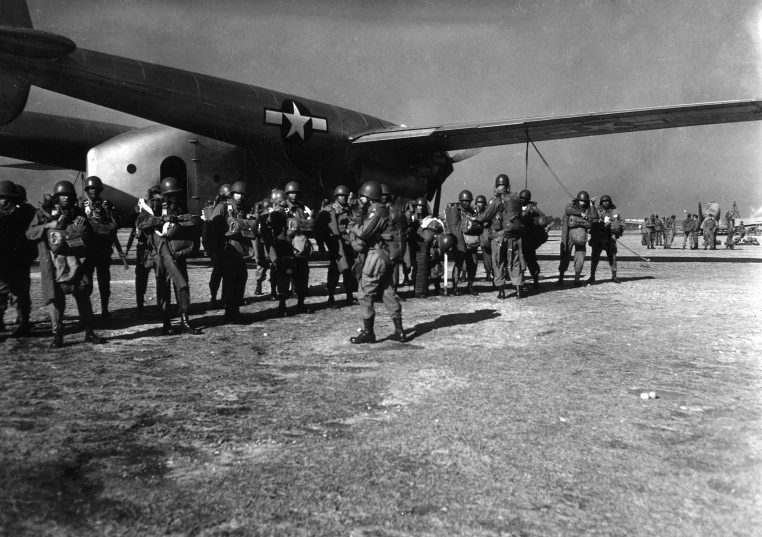 an old po shows men standing near a large military plane