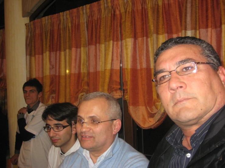 a group of men standing in front of curtained window