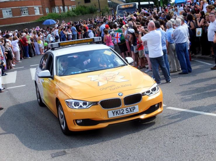 a yellow car that is parked in front of a crowd