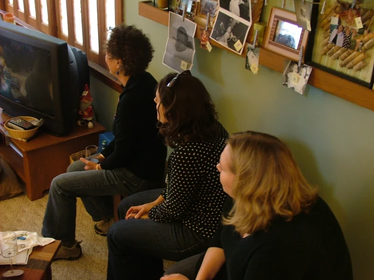three women are playing video games while sitting in the room