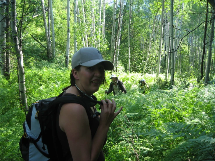 the man wearing a hat and backpack is walking through the woods