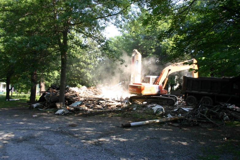 a dump truck next to a pile of rubble with trees in the background