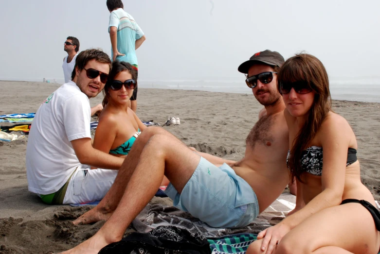 the group of friends are sitting on the beach