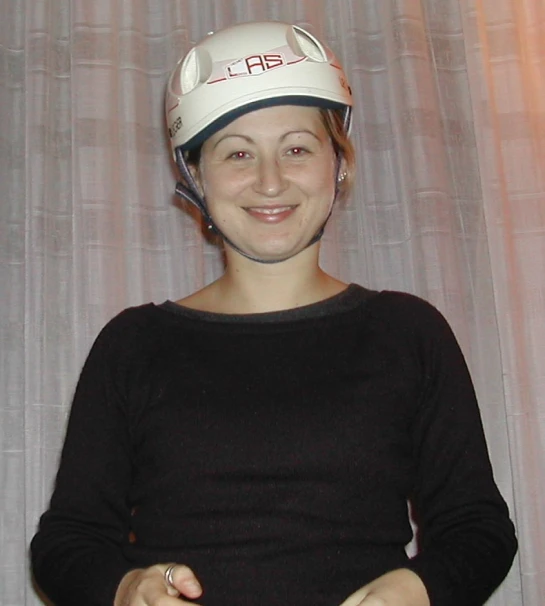 a woman standing in front of a curtain with a white helmet on her head