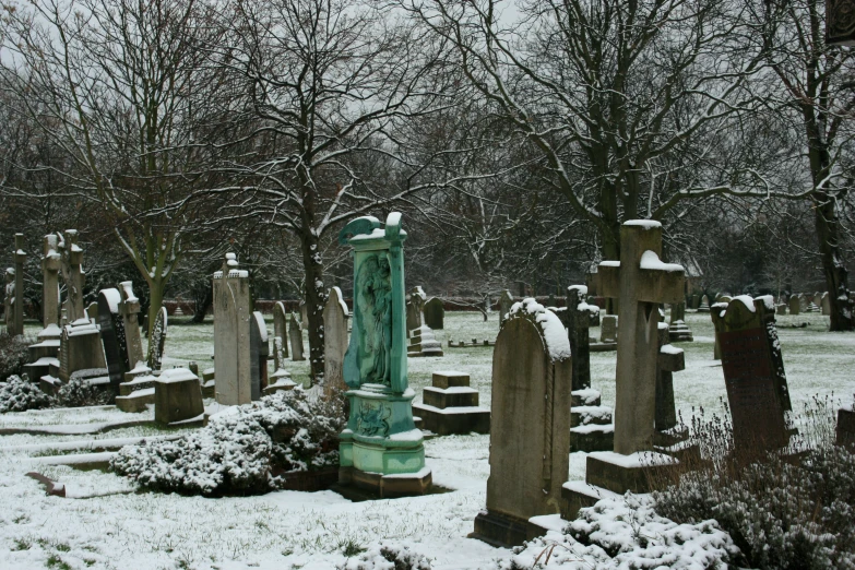 a cemetery with snow on the ground, trees and a lot of tombstones