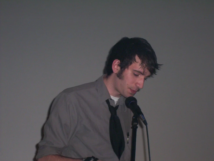 a man in a tie playing a guitar in front of a microphone