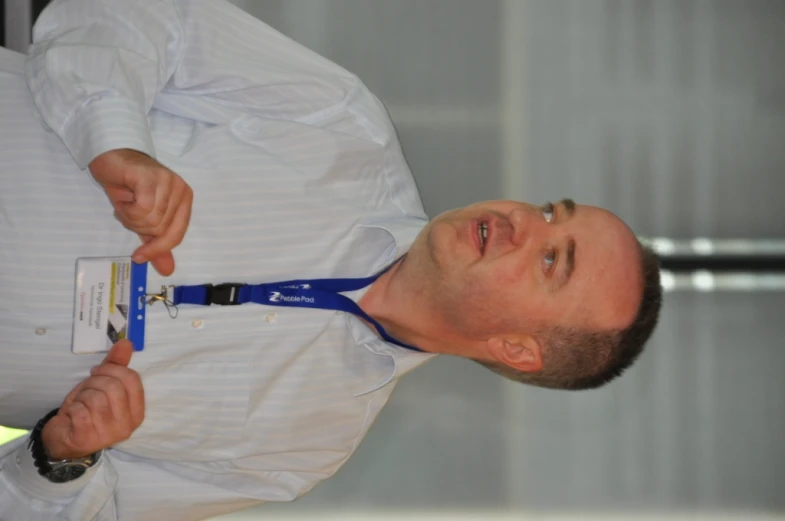 a man wearing a lanyard name badge in his hand