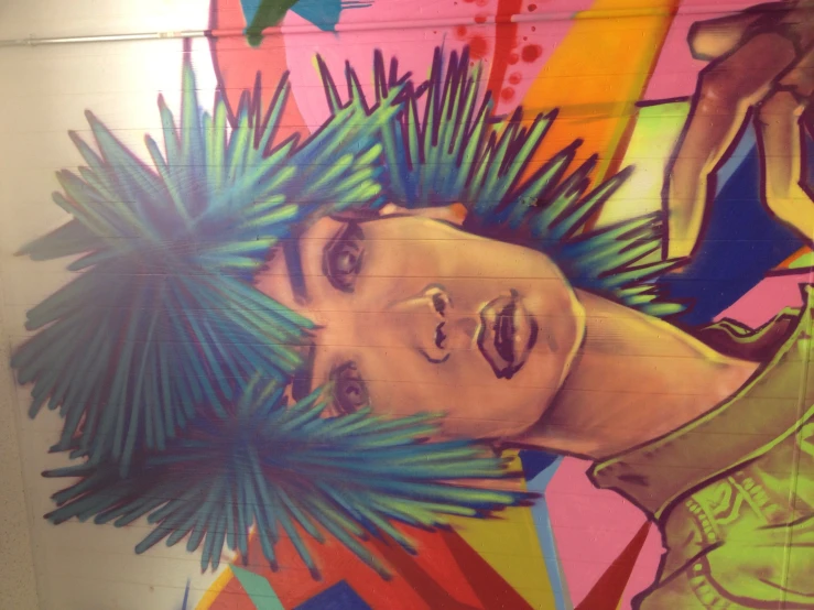 a mural on the side of a building depicting a  with green hair and blue and purple mohawks
