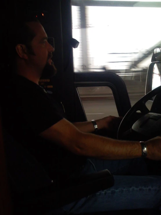 a man sitting on the driver's wheel of a bus