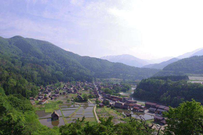 the village in the valley has green trees surrounding it