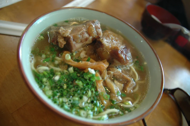 a bowl with beef and noodle soup on a table