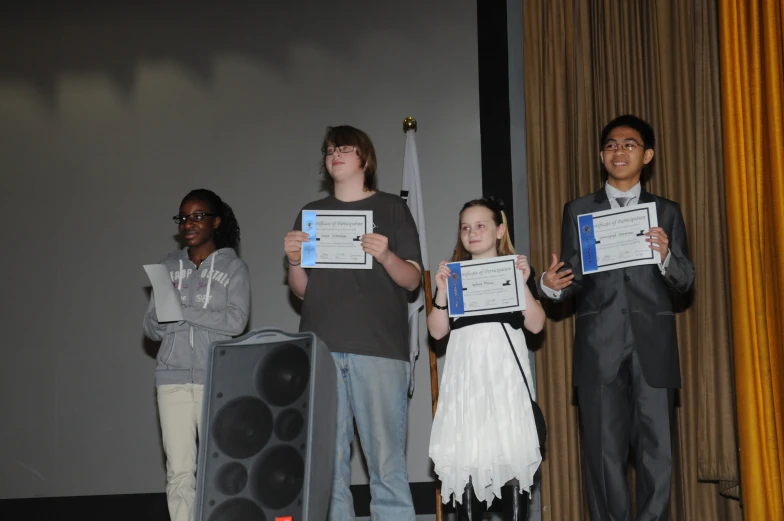 three people on stage with one holding up two large awards