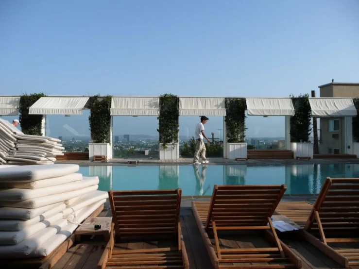 people are walking around in chairs near an empty pool