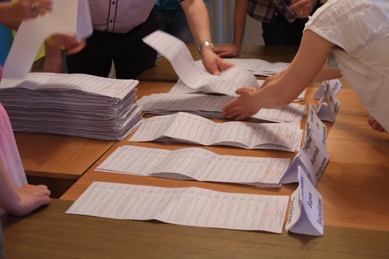 several people around a wooden table full of papers