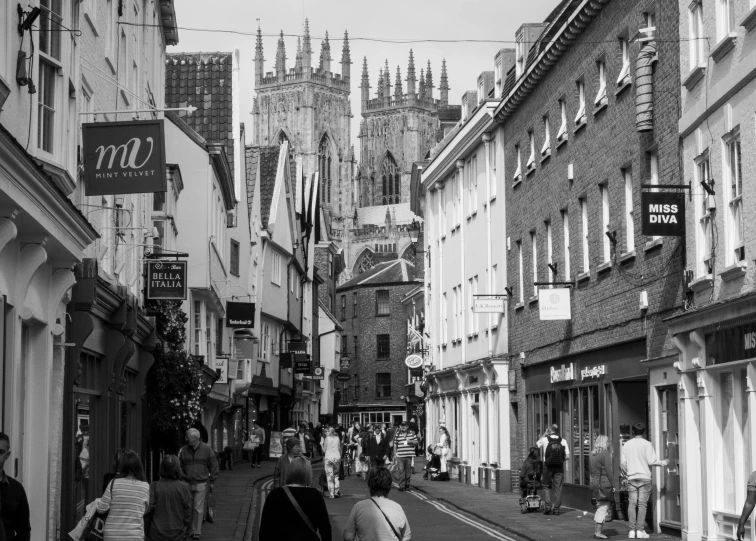 a street lined with buildings, people and tall gothic towers