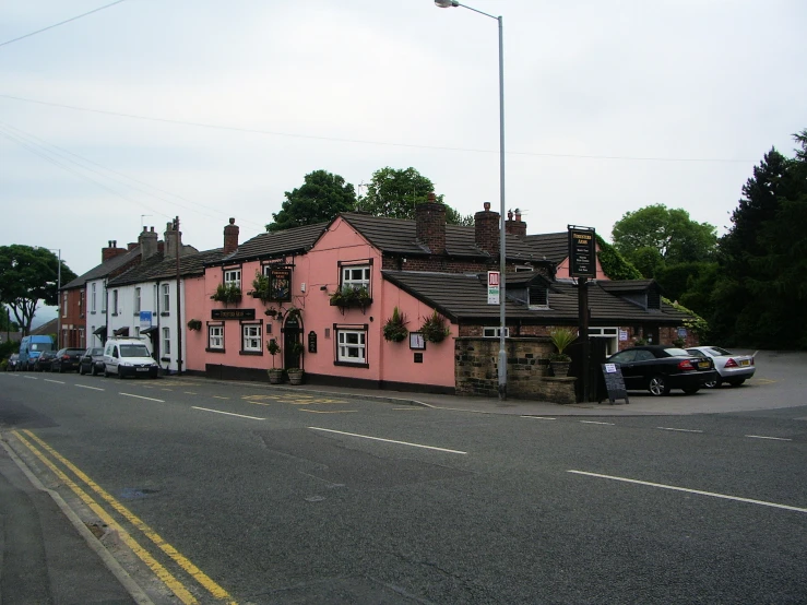a pink house with two story windows sits on a road