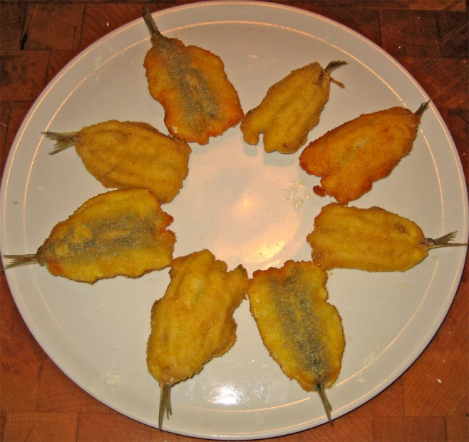 a white plate topped with fried food on top of a wooden table