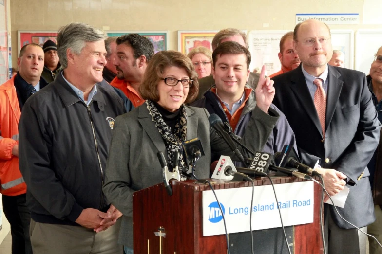 a bunch of people with flags and microphones in front of a man at a podium