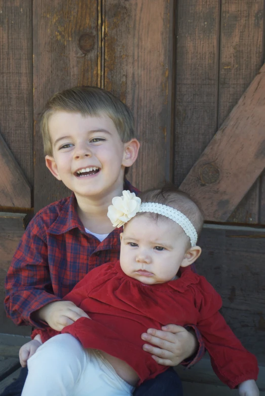 there is a small child holding another child on his lap