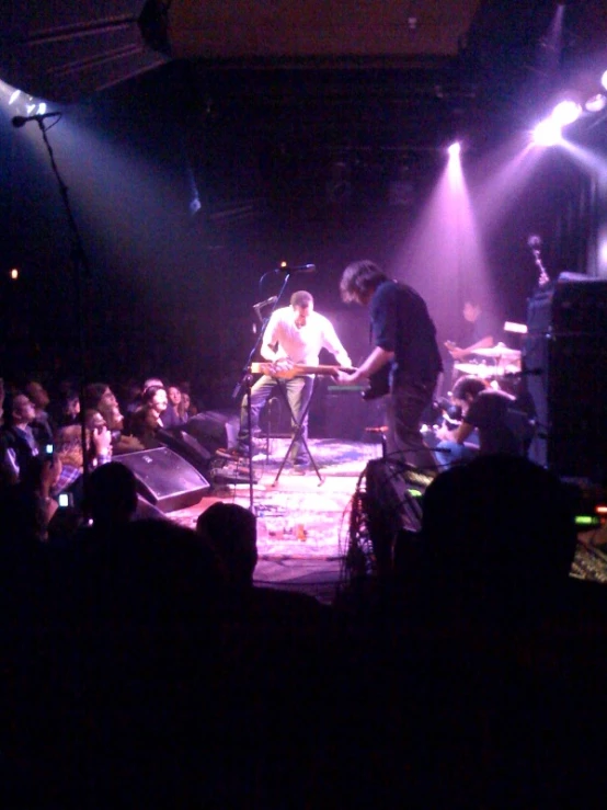 two people standing on stage and playing instruments