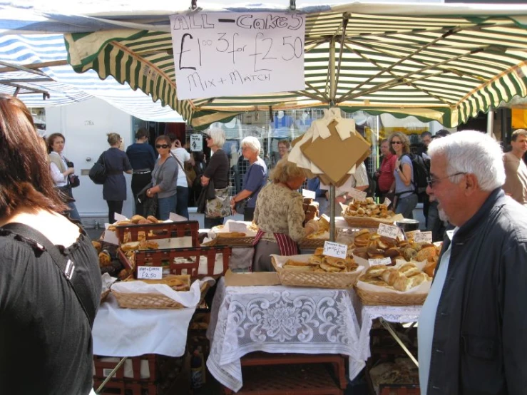 a group of people standing around a table full of food