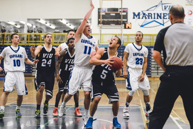 a basketball player jumps in the air for a basketball while playing against defenders