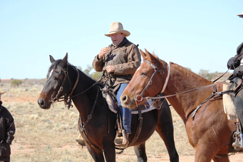 several cowboys sit on horses and look towards the camera