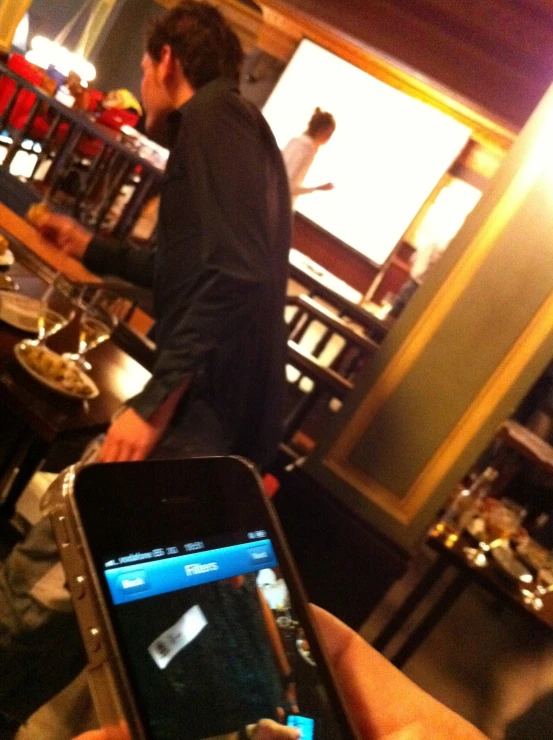 a man standing behind a bar while looking at his cellphone