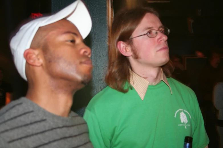 a man looks up while another man with a cap sits next to him