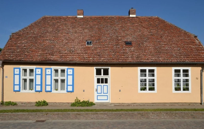 a beige brick building has blue shutters on the windows