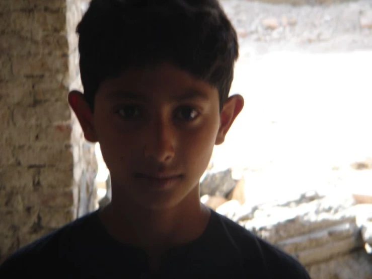 the boy is wearing black and standing near a wall