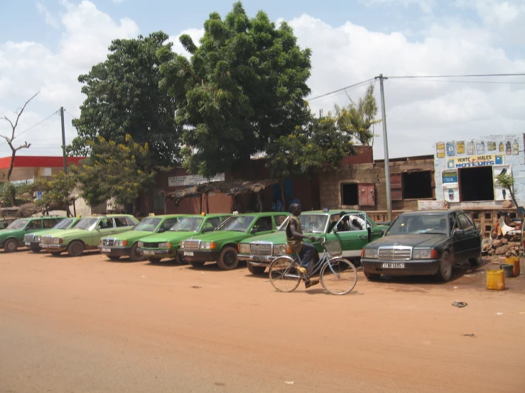 a man rides his bicycle past a line of parked cars