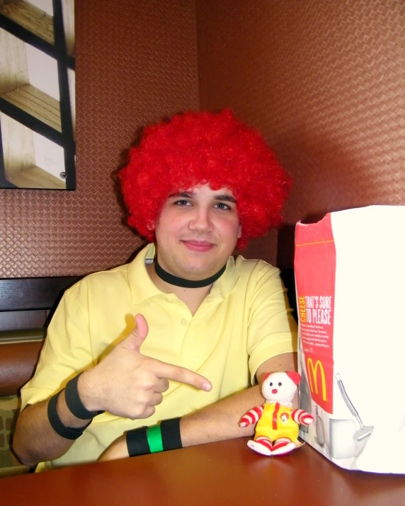 a young person with a red wig sitting next to a bag