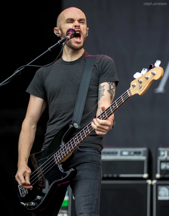 a man standing in front of a microphone playing guitar