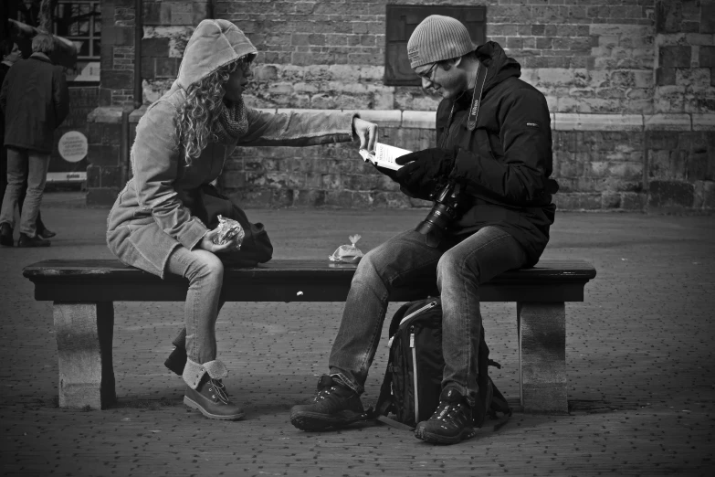 a man reading a book to a woman on a bench